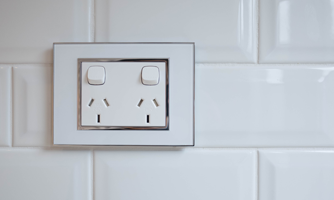 A photograph of a dual power socket on white tiles.